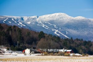 The snowy ski trails of Stowe Mountain Resort above an agricultural scene in Stowe, Vermont