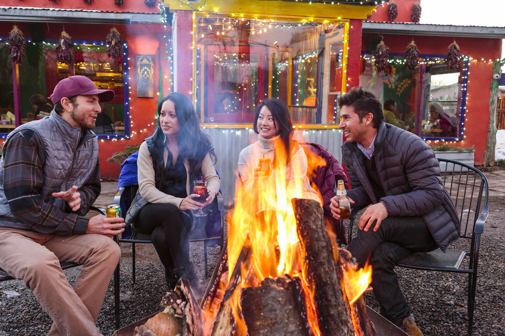Friends gathered around a fire outdoors with drinks in Taos, New Mexico

