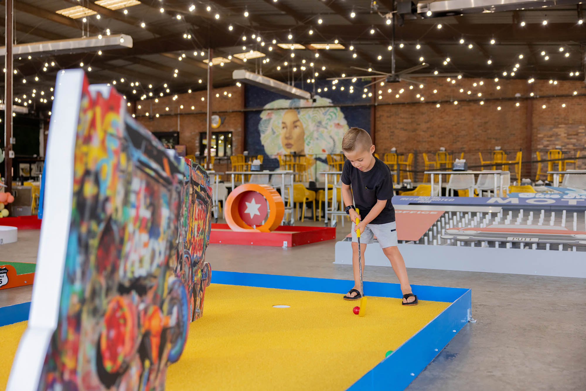 A young boy playing mini golf at Mother Road Market in Tulsa, Oklahoma; Credit: Valerie Wei-Haas
