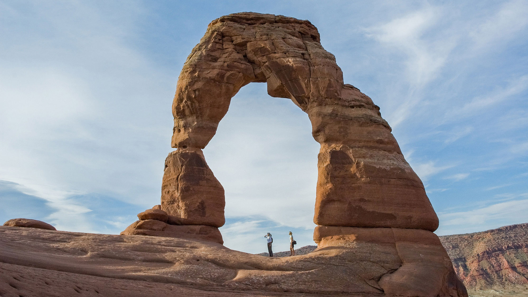Hikers under Delicate Arch at Arches National Park in Utah