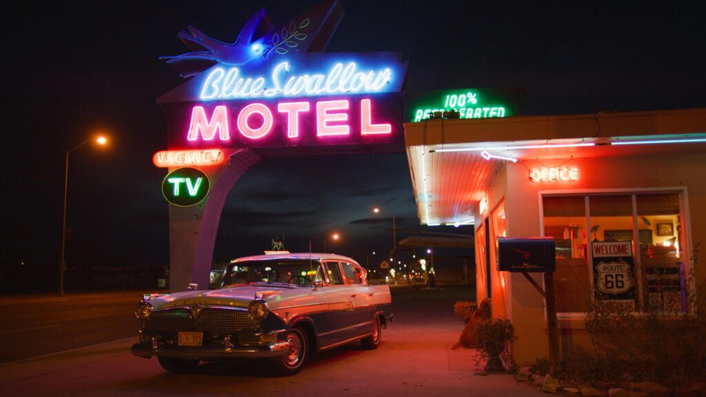A vintage car and neon sign with word illuminated outside the Blue Swallow Motel in Tucumcari, New Mexico