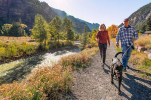 A couple and their dog walking the Uncompahgre River Walk in Ouray, Colorado; Credit: Trav Perk