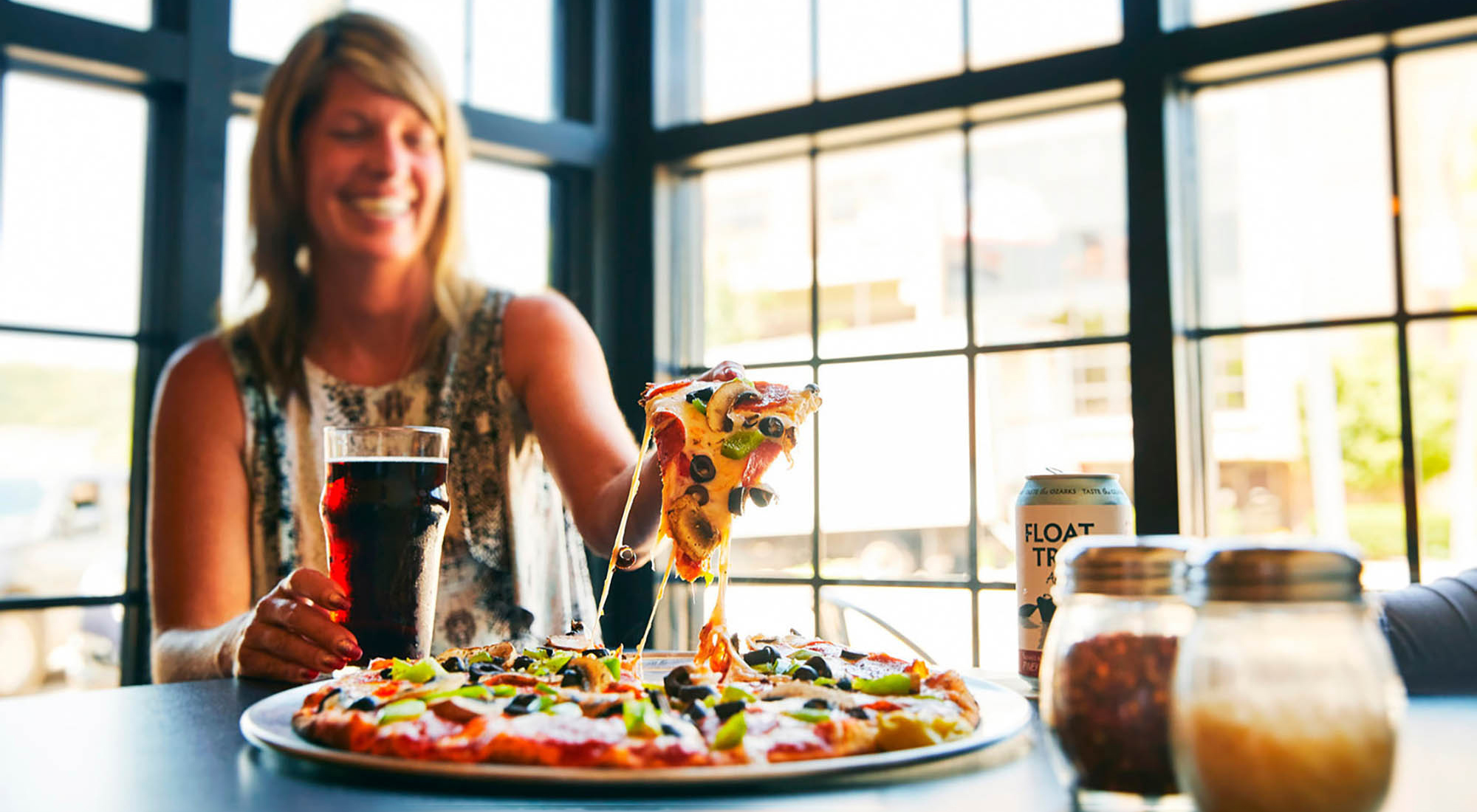 Une femme en train de manger une pizza chez PaPPo’s Pizzeria &amp; Pub St. Robert, Missouri; Crédit : Office du tourisme du comté de Pulaski