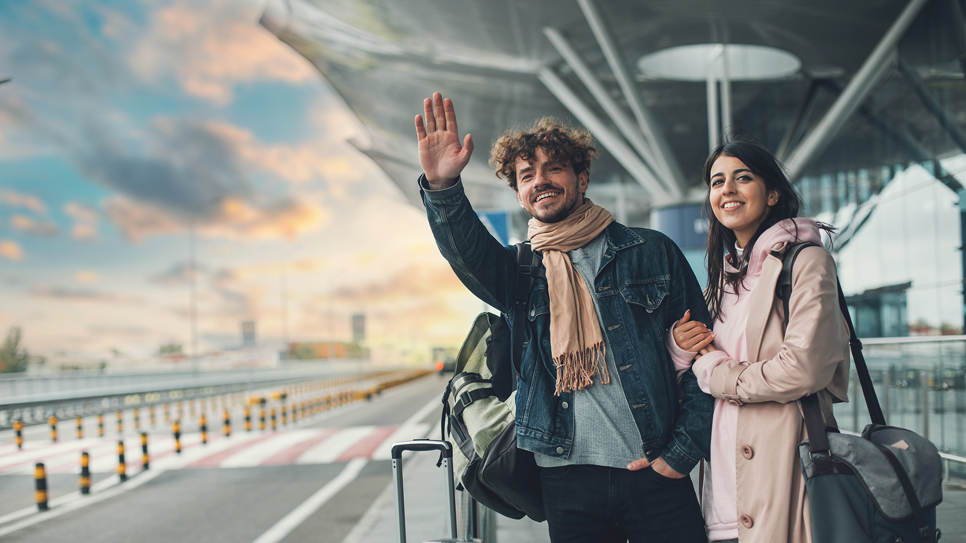 Una pareja en un aeropuerto parando un taxi