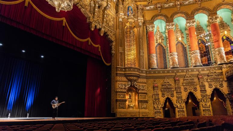 Man plays guitar in a theatre
