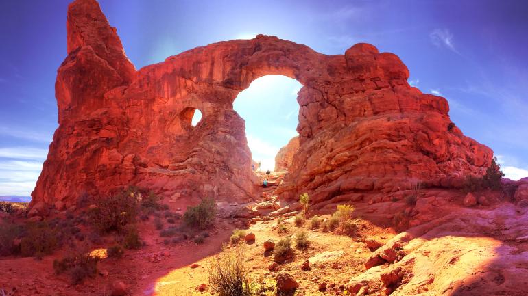 Hikers under rock formation in Moab, Utah