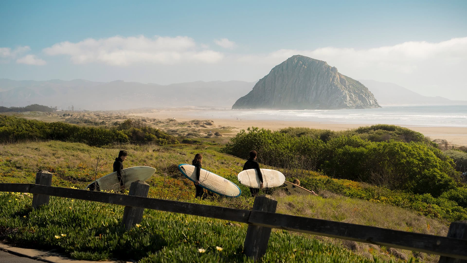 Surfistas indo para a Morro Strand State Beach em Morro Bay, California; Crédito: Visit SLO CAL