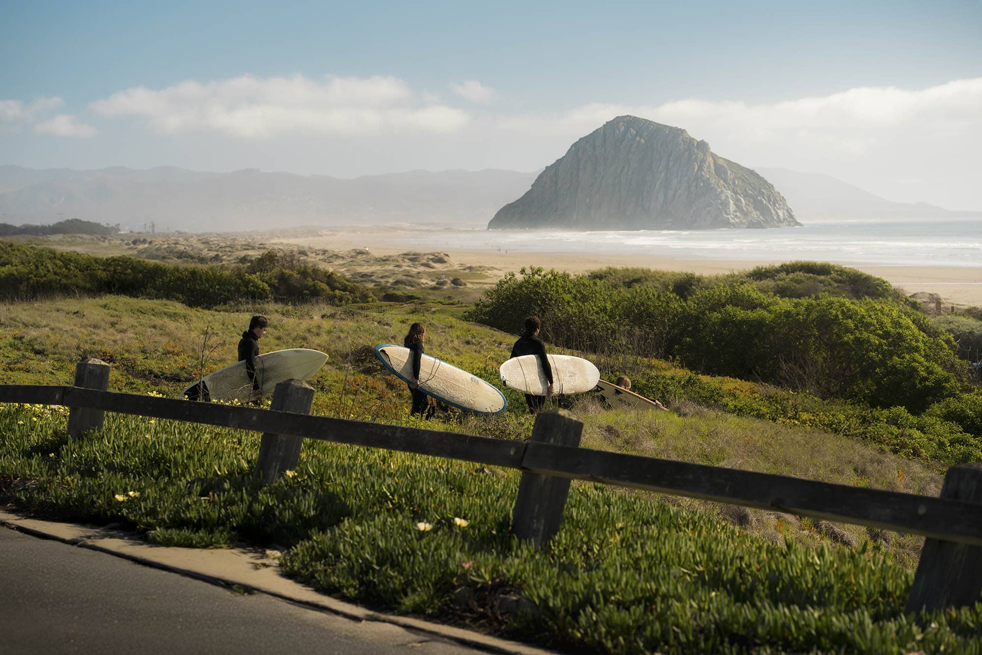 Surfers heading to Morro Strand State Beach in Morro Bay, California